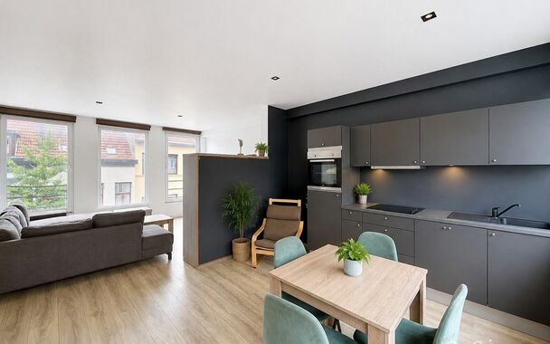 Mooi appartement op de tweede verdieping met een riant terras. Inkomhal, lichtrijke leefruimte (ca 37m&sup2;) met een open ge&iuml;nstalleerde keuken. De moderne keuken is uitgerust met keramische kookplaat, oven, dampkap, vaatwasser en koelkast met vriesvak. Van