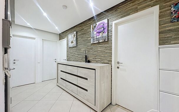 Dit appartement op de tweede verdieping werd recent gerenoveerd. Via de inkomhal bereik je vooraan de lichte woonkamer op tegelvloer. Aansluitend de ingerichte keuken uitgerust met gaskookfornuis, dubbele spoelbak, oven, koelkast met vriesvak en voldoende