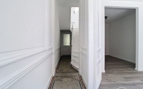 Bij het binnenkomen word je verwelkomd in een authentieke inkomhal, stijlvol afgewerkt met sierlijke molures en een karaktervolle mozaïekvloer. Vanuit de hal wandel je door naar de leefruimte aan de achterzijde van de woning, waar een skylight zorgt voor