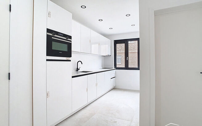 Stap binnen in dit smaakvol afgewerkte appartement, gelegen in een klassevol gerenoveerd gebouw op wandelafstand van het centrum van Edegem.
De inkomhal biedt directe toegang tot de moderne keuken, volledig uitgerust met hoogwaardige Siemens-toestellen 
