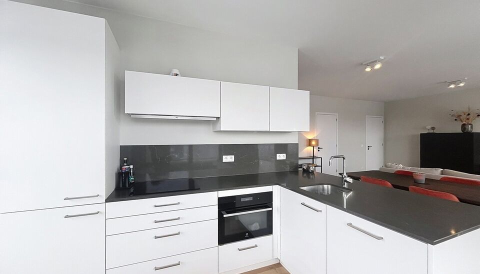 Verzorgd volledig ingericht hoekappartement op de 8e verdieping met een open uitzicht op het MAS en over de Leie. Inkomhal met vestiairekast en apart toilet. Ruime woon- en eetkamer op parketvloer (ca. 36m&sup2;) welke toegang geeft tot het overdekte terras. 