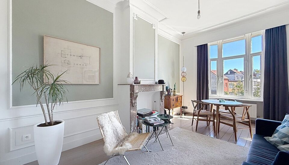Charmant instapklaar appartement op de 2e verdieping met aangenaam open uitzicht. Inkomhal met vestiairekast. Lichtrijke woonkamer (ca. 22m&sup2;) op authentieke plankenvloer en een schouwelement. Aansluitend de half open keuken voorzien van gasfornuis, dampk