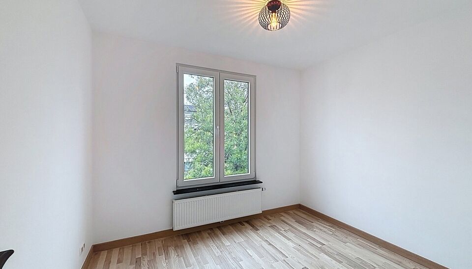 Bij het betreden van dit volledig gerenoveerde appartement wordt u verwelkomd in een stijlvolle inkomhal met een elegante, afgeronde deuropening.
Direct aan de inkom bevindt zich een bureauruimte met parketlaminaat en een gloednieuw raam, ideaal voor thui