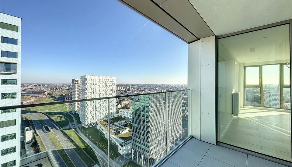 Luxe nieuwbouw appartement op de 20e verdieping met 270 graden uitzicht over Antwerpen, Park Spoor Noord, het Eilandje en de dokken. De lichtrijke leefruimte (ca. 26 m&sup2;) met open  keuken (ca. 6 m&sup2;) is voorzien van een keramische kookplaat, dampkap, koel