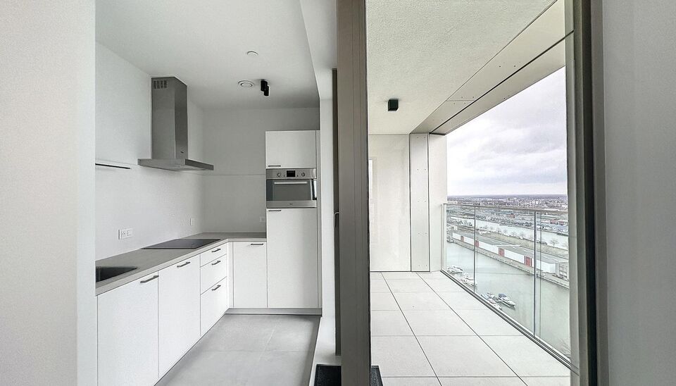 Luxe nieuwbouw appartement op de 20e verdieping met 270 graden uitzicht over Antwerpen, Park Spoor Noord, het Eilandje en de dokken. De lichtrijke leefruimte (ca. 26 m&sup2;) met open  keuken (ca. 6 m&sup2;) is voorzien van een keramische kookplaat, dampkap, koel