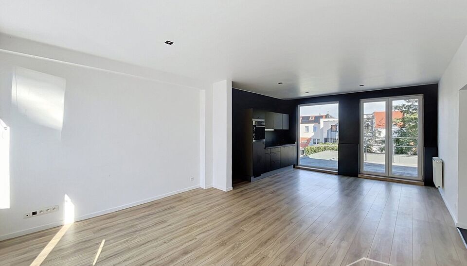 Mooi appartement op de tweede verdieping met een riant terras. Inkomhal, lichtrijke leefruimte (ca 37m&sup2;) met een open ge&iuml;nstalleerde keuken. De moderne keuken is uitgerust met keramische kookplaat, oven, dampkap, vaatwasser en koelkast met vriesvak. Van