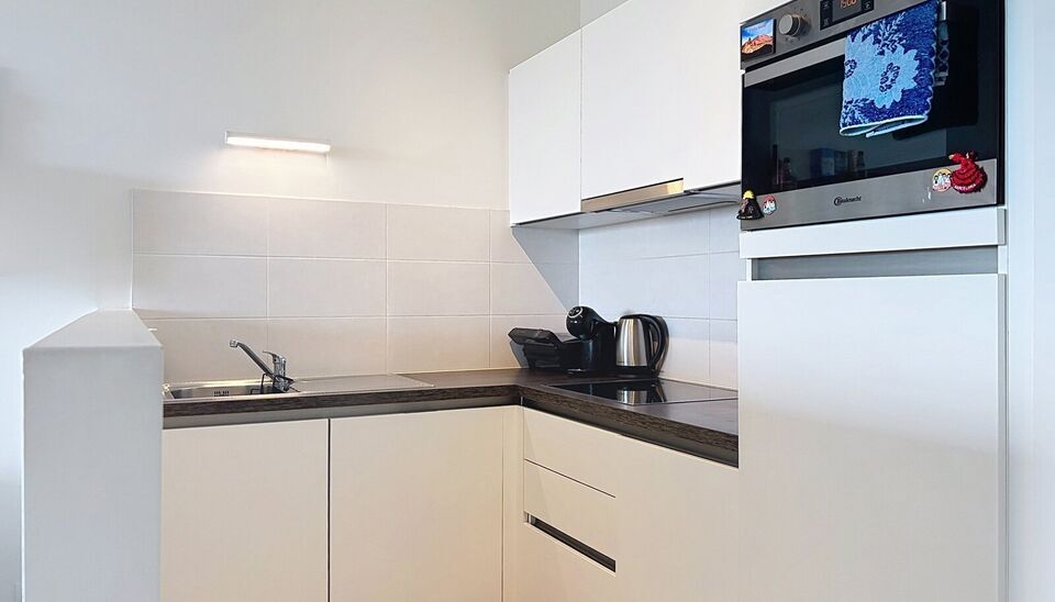 Dit energiezuinig appartement bevindt zich in een recent gebouw (2018) nabij de Slachthuissite. U betreedt het appartement via de inkomhal (ca.7 m&sup2;) met voldoende kastruimte en apart toilet. Lichtrijke woonkamer op keramische parket met een open keuken. 