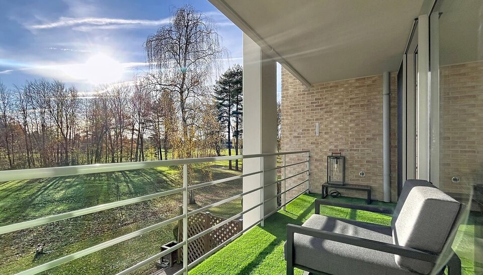 Lichtovergoten en zonnig appartement met een prachtig open uitzicht op de holes van de Golf van Brasschaat. Bij binnenkomst een ruime inkomhal met apart toilet. De uitnodigende woon- en eetkamer op parketvloer (ca. 31m²), biedt toegang tot het zonnige te