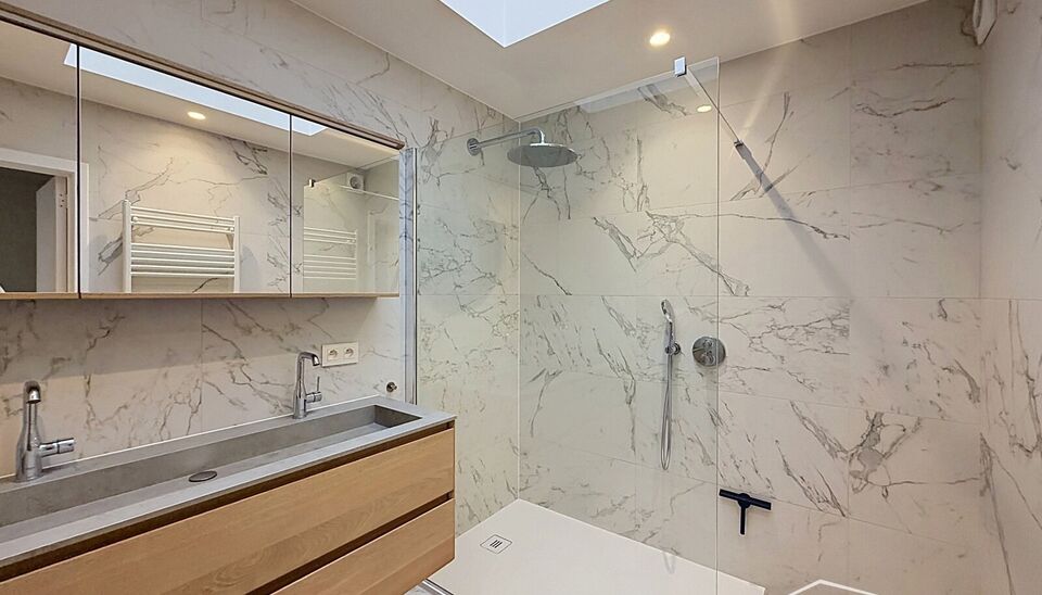 Lichtovergoten en zonnig appartement met een open uitzicht op een groen pleintje. Bij binnenkomst een ruime inkomhal met apart toilet met handenwasser. De uitnodigende woon- en eetkamer op keramische tegelvloer (ca. 30m&sup2;), biedt toegang tot het zonnige t