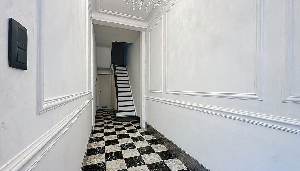 In een charmant gebouw met herenhuis-allure ontdek je deze unieke duplexwoning die eerder dienst deed als twee aparte appartementen, maar nu stijlvol werd samengevoegd tot een ruimtelijke gezinswoning vol karakter.
Via de aparte privé-inkomhal stap je bi