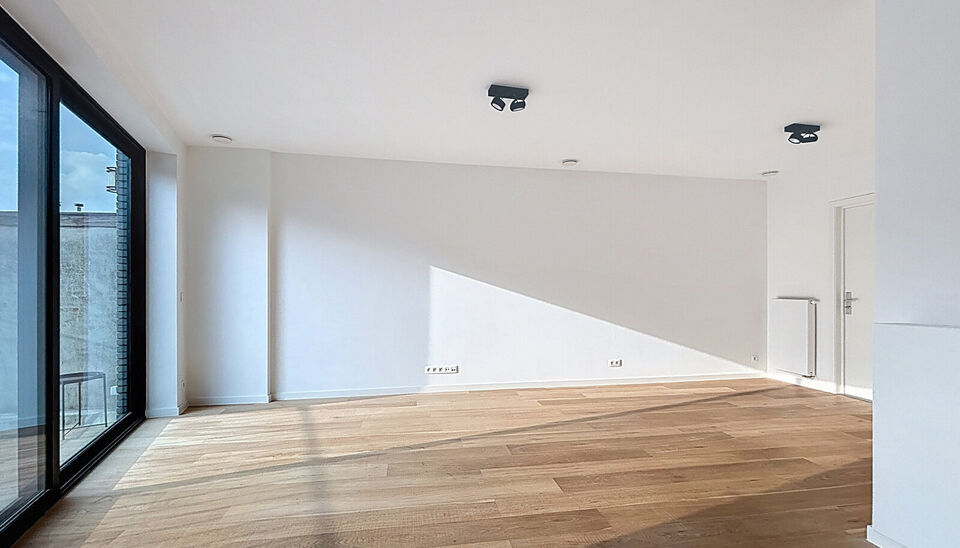 Het appartement bevindt zich op de zesde verdieping, achteraan in residentie KPlaza, een modern, energiezuinig en stijlvol nieuwbouwproject dat werd opgeleverd in 2019. Bij het betreden van de leefruimte valt meteen de mooie parketvloer op, evenals de kwa