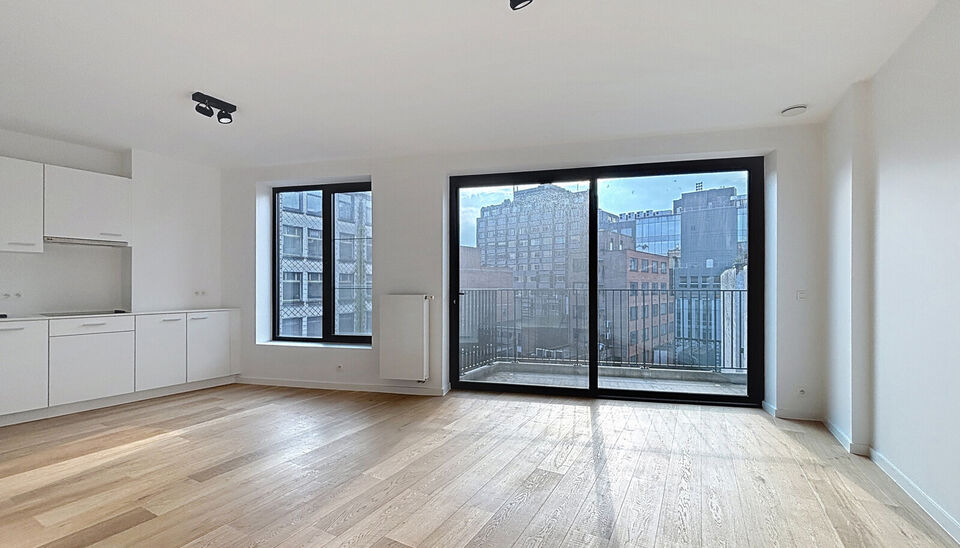 Het appartement bevindt zich op de zesde verdieping, achteraan in residentie KPlaza, een modern, energiezuinig en stijlvol nieuwbouwproject dat werd opgeleverd in 2019. Bij het betreden van de leefruimte valt meteen de mooie parketvloer op, evenals de kwa