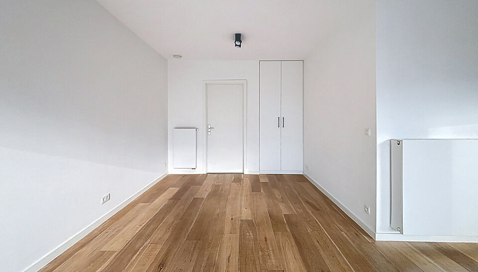 Het appartement bevindt zich op de zesde verdieping, achteraan in residentie KPlaza, een modern, energiezuinig en stijlvol nieuwbouwproject dat werd opgeleverd in 2019. Bij het betreden van de leefruimte valt meteen de mooie parketvloer op, evenals de kwa
