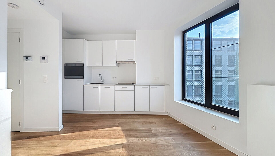 Het appartement bevindt zich op de zesde verdieping, achteraan in residentie KPlaza, een modern, energiezuinig en stijlvol nieuwbouwproject dat werd opgeleverd in 2019. Bij het betreden van de leefruimte valt meteen de mooie parketvloer op, evenals de kwa